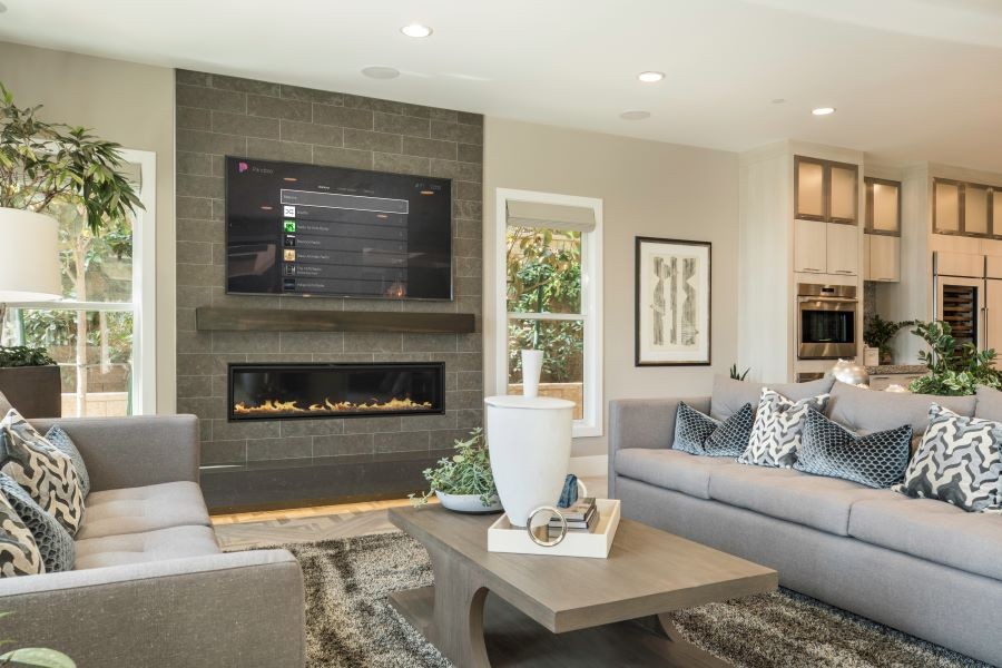 A living room with in-ceiling speakers and a Control4 platform displaying a Pandora playlist on the TV screen. 